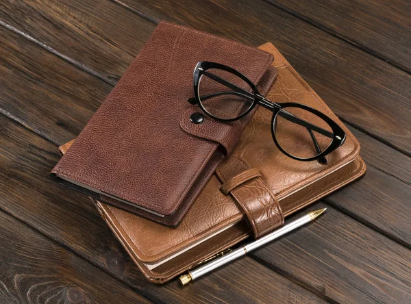 Twee Notitieboekjes Pen Bril Een Houten Ondergrond — Stockfoto