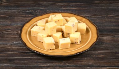 Tahta bir arka planda tabakta peynir küpleri