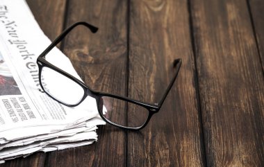 Ahşap bir arka planda gözlük ve gazeteler