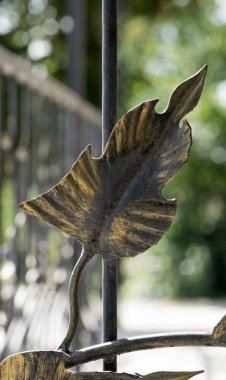 Altın yaprak şeklinde dekoratif elementlerle dövülmüş metal çitler.