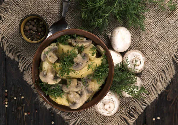 Potatoes with mushrooms on a wooden background,