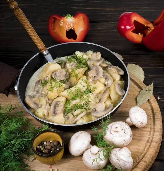 Potatoes with mushrooms in a skillet on a wooden background