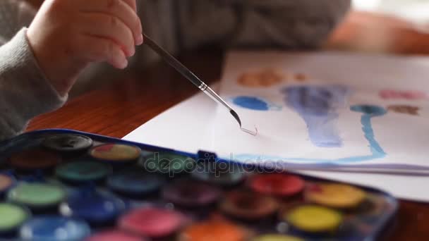 Mladá dívka malba na papírové archy s akvarelový štětec. Detailní záběr. — Stock video