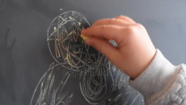 Jong meisje op een schoolbord met een stuk krijt schrijven. Close-up. — Stockvideo