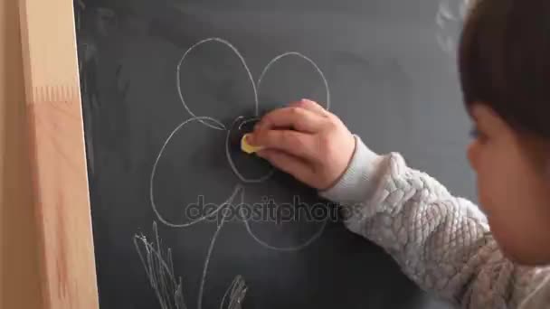 Ung flicka skriver på svarta tavlan med en bit krita. Närbild. — Stockvideo