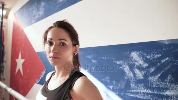 Boxer féminin appuyé sur les cordes d'un ring de boxe et regardant la caméra . — Video