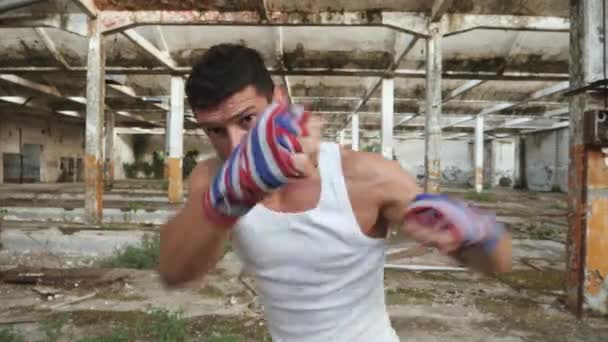 Joven boxeador masculino haciendo ejercicio de boxeo en la sombra . — Vídeos de Stock