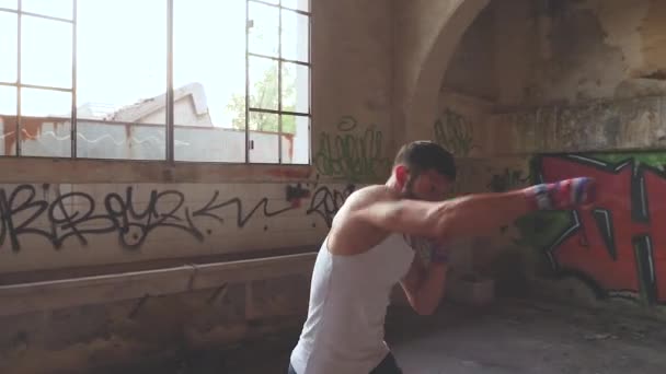 Мужчина боксер, занимающийся теневым боксом в старом заброшенном здании — стоковое видео