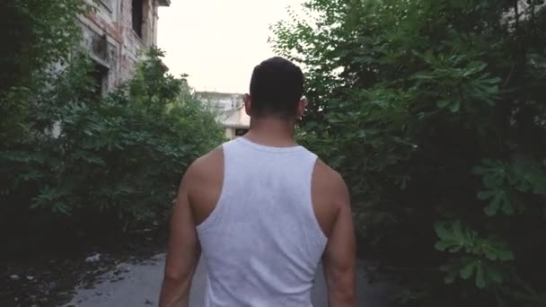 Hombre musculoso caminando en una fábrica abandonada demolida — Vídeo de stock