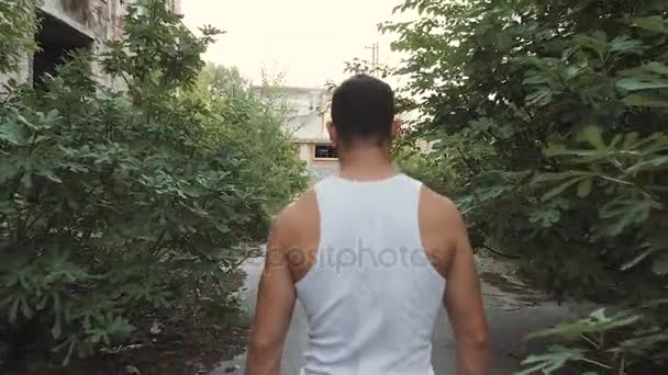 Homem musculoso andando em uma fábrica abandonada demolida — Vídeo de Stock