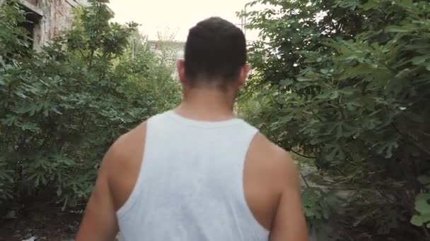 Muscular man walking in a demolished abandoned factory — Stock Video