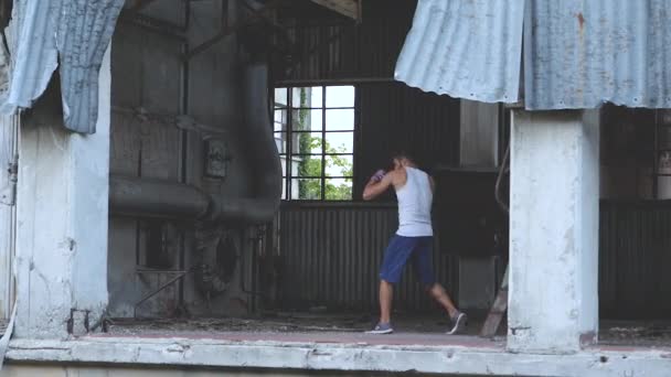 Mannelijke bokser doen schaduw boksen oefening in een oude verlaten fabriek — Stockvideo