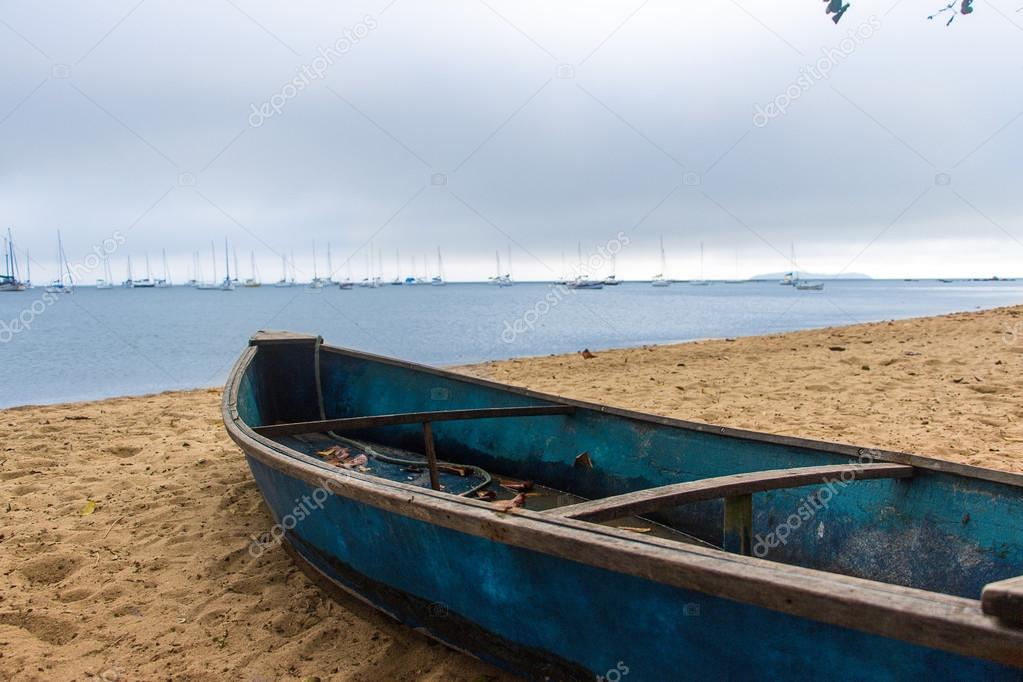 Blue boat on the beach sand on a cloudy day - Florianopolis, Brazil