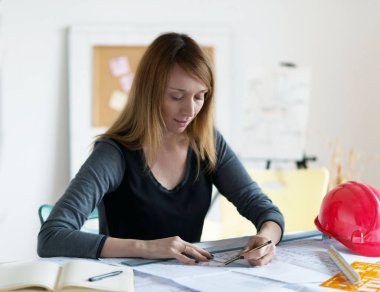 Ofiste çalışan Kızıl saçlı kadın gülümseyen genç mimar. 