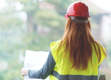 Kızıl saçlı kadın mimar kırmızı koruyucu miğfer. 