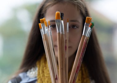 Gülümseyen genç kadın ressam iki fırçaları ile. 