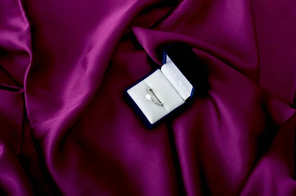 Zásnubní prsten na fialové saténové. — Stock fotografie