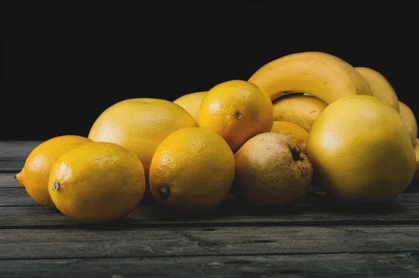 Bos van vers geel fruit op een oud houten tafel. — Stockfoto