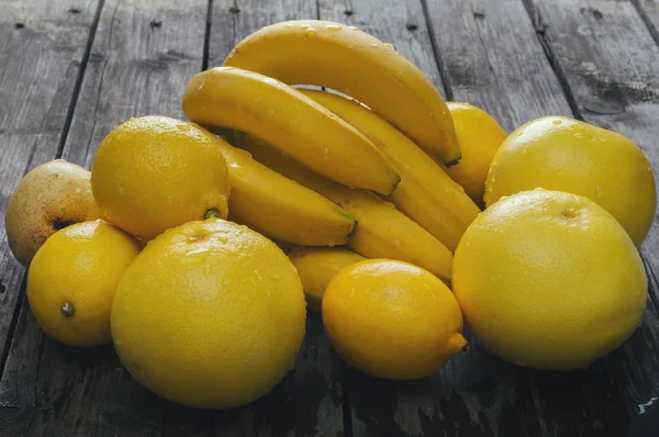 Bos van vers geel fruit op een oud houten tafel. — Stockfoto