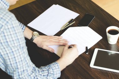 Genç erkek iş girişimci ofisinde bazı kağıtları imzaladı. 