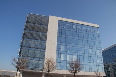 Şehir metropolü modern mimarisi. Dışarısı cam duvarlarla kaplı, etrafındaki binaları yansıtıyor. İş ve ofis amaçları için yepyeni binalar