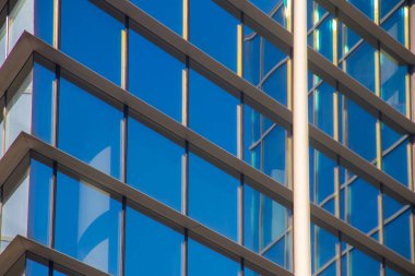 Şehir metropolü modern mimarisi. Dışarısı cam duvarlarla kaplı, etrafındaki binaları yansıtıyor. İş ve ofis amaçları için yepyeni binalar