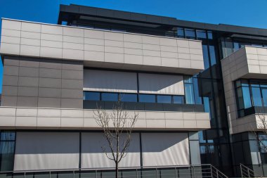 Şehir metropolü modern mimarisi. Dışarısı cam duvarlarla kaplı, etrafındaki binaları yansıtıyor. İş ve ofis amaçları için yepyeni binalar