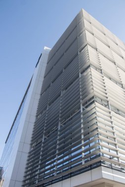 Şehir metropolü modern mimarisi. Dışarısı cam duvarlarla kaplı, etrafındaki binaları yansıtıyor. İş ve ofis amaçları için yepyeni binalar