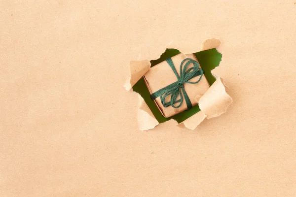 Pequeña caja de regalo en un agujero en papel — Foto de Stock