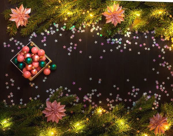 Fir takken, confetti sterren en kerstballen op donkere houten achtergrond — Stockfoto