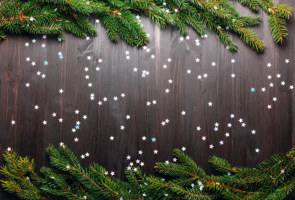 Fir boomtakken en confetti op donkere achtergrond, plat gelegd. — Stockfoto