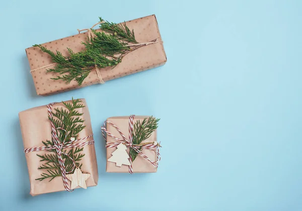 Різдвяні подарункові коробки, загорнуті в ремісничий папір на синьому папері — стокове фото