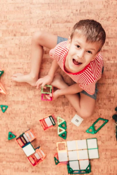 Laughing boy plays with magnetic constructor in kids room — Stock Photo, Image