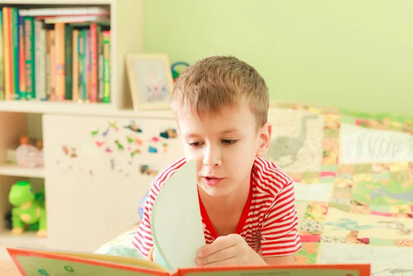 Kind liegt auf Bett und liest ein Buch — Stockfoto