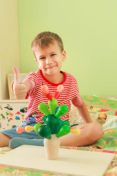 Un bambino gioca con il giocattolo. Bambino mostra pollice in su segno — Foto Stock