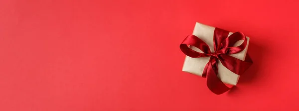 Caixa de presente de Natal pequeno no fundo vermelho — Fotografia de Stock