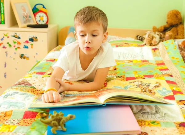 Little child reading book while laying on bed — Stock Photo, Image