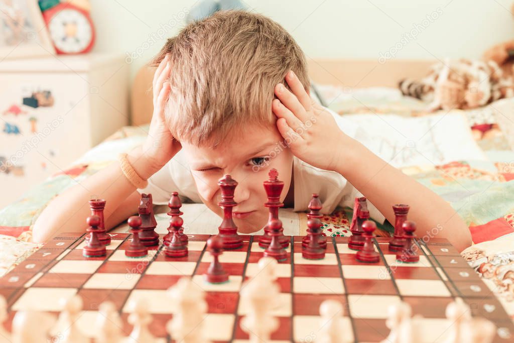 Small boy is hardly concentrated on playing chess game