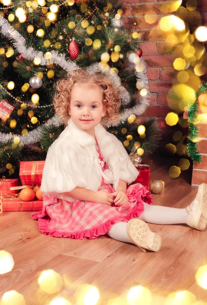 Pequeña niña sentada cerca del árbol de Navidad decorado —  Fotos de Stock