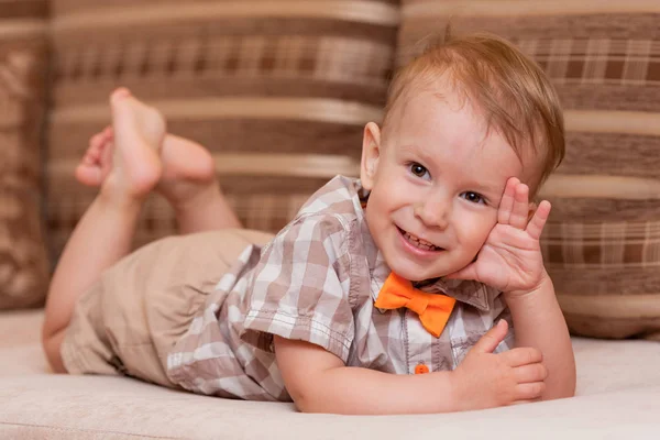 シャツを着た可愛い赤ちゃんと、お腹に蝶ネクタイが横になって笑っている。 — ストック写真