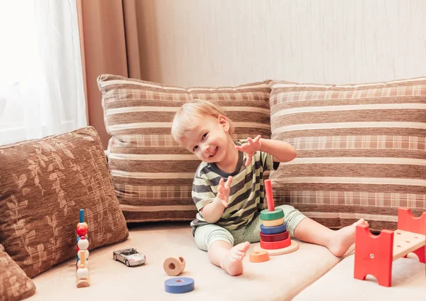 Мальчик сидит на диване и играет с развивающими игрушками. — стоковое фото