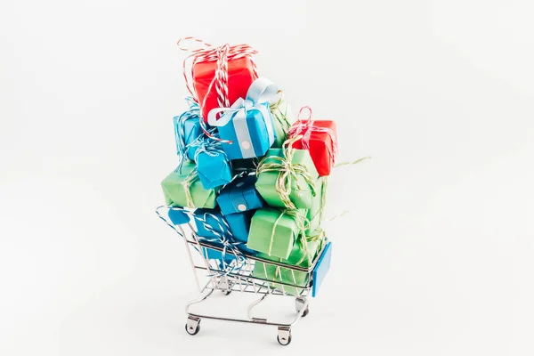 Wagen winkelwagen gevuld met een heleboel papier verpakt geschenkdozen op lichte achtergrond. — Stockfoto