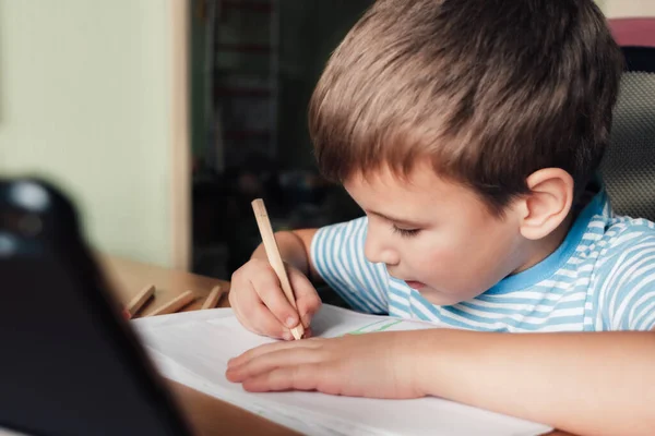 Kecil anak duduk di meja dan menggambar album surat dengan pensil berwarna — Stok Foto