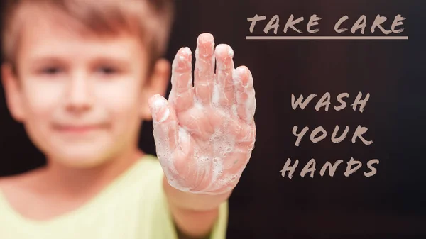 Front view on boys hand with soap foam and text wash your hands, focus on hand, personal hygiene concept
