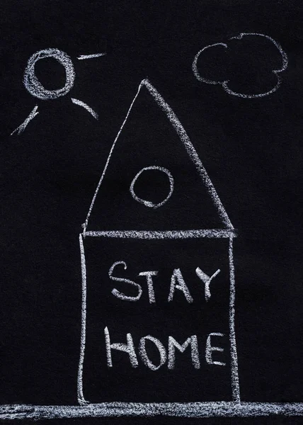 Drawing with chalk on a black blackboard, house with text Stay Home. Concept of virus protection