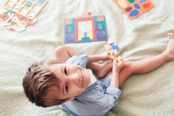 Szczęśliwy Chłopiec Siedzi Łóżku Układa Puzzle Widok Góry Dziecko Patrzy — Zdjęcie stockowe