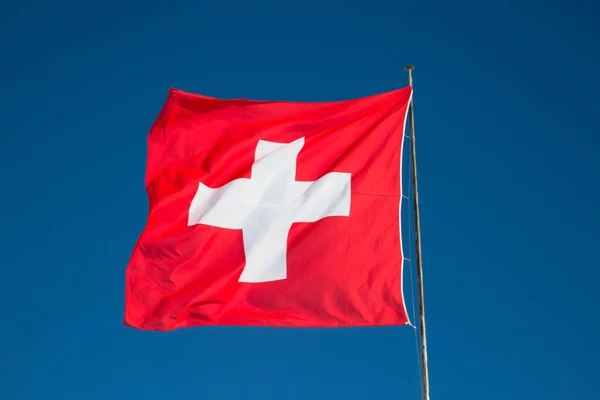 Swiss flag against blue sky — Stock Photo, Image