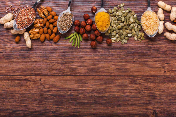 Ассорти орехов в белой миске, тарелка на деревянной поверхности. Вид сверху с пространством для копирования
