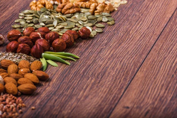 Surtido de frutos secos en tazón blanco, plato en la superficie de madera. Vista superior con espacio de copia — Foto de Stock