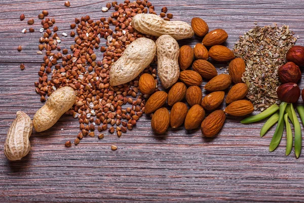 Assorted nuts in white bowl, plate on wooden surface. Top view with copy space — Stock Photo, Image